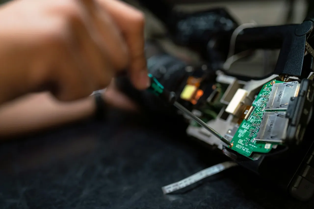 Technician handling an electronic circuit board during repair